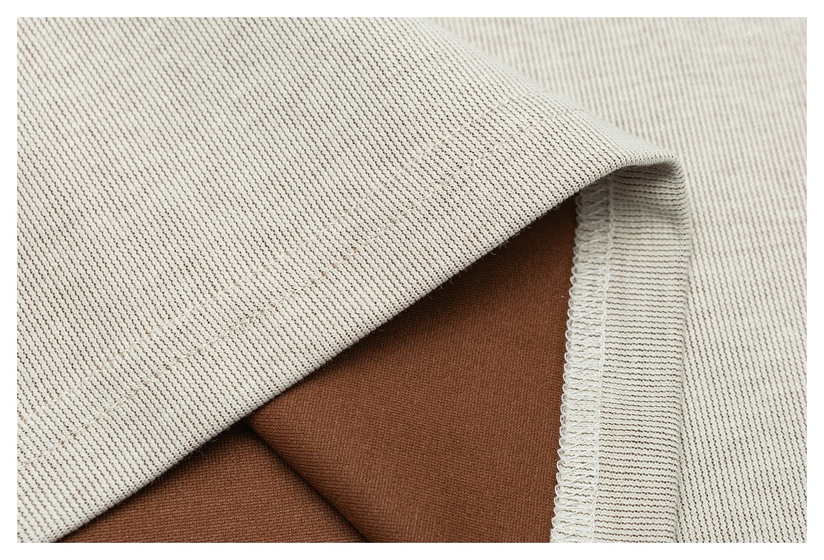 Close-up of cream ribbed knit fabric folded over brown fabric, showing a stitched edge.