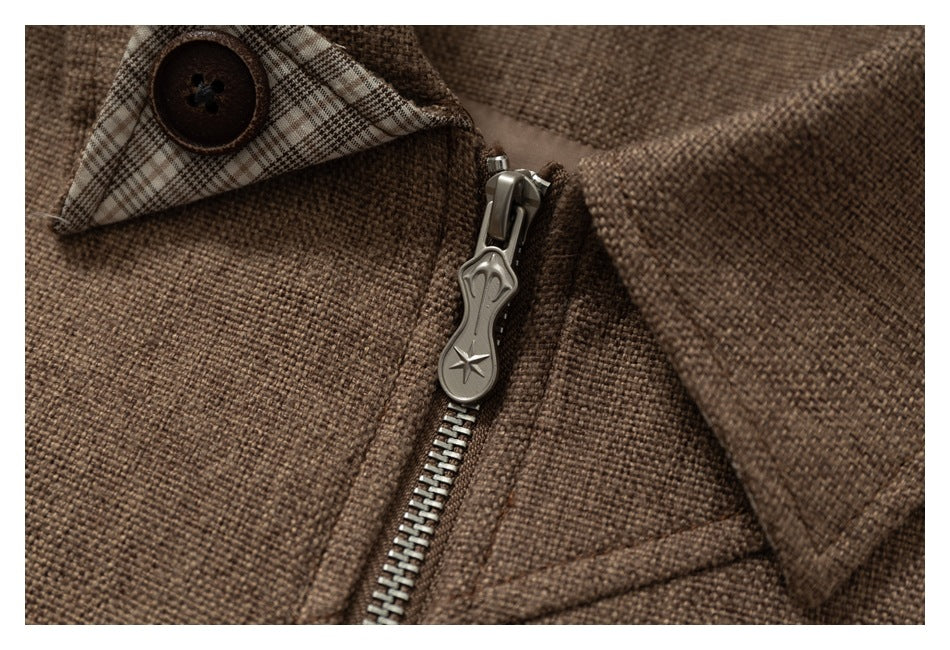 Close-up of the jacket’s metal zipper pull, plaid accent, and brown textured fabric.