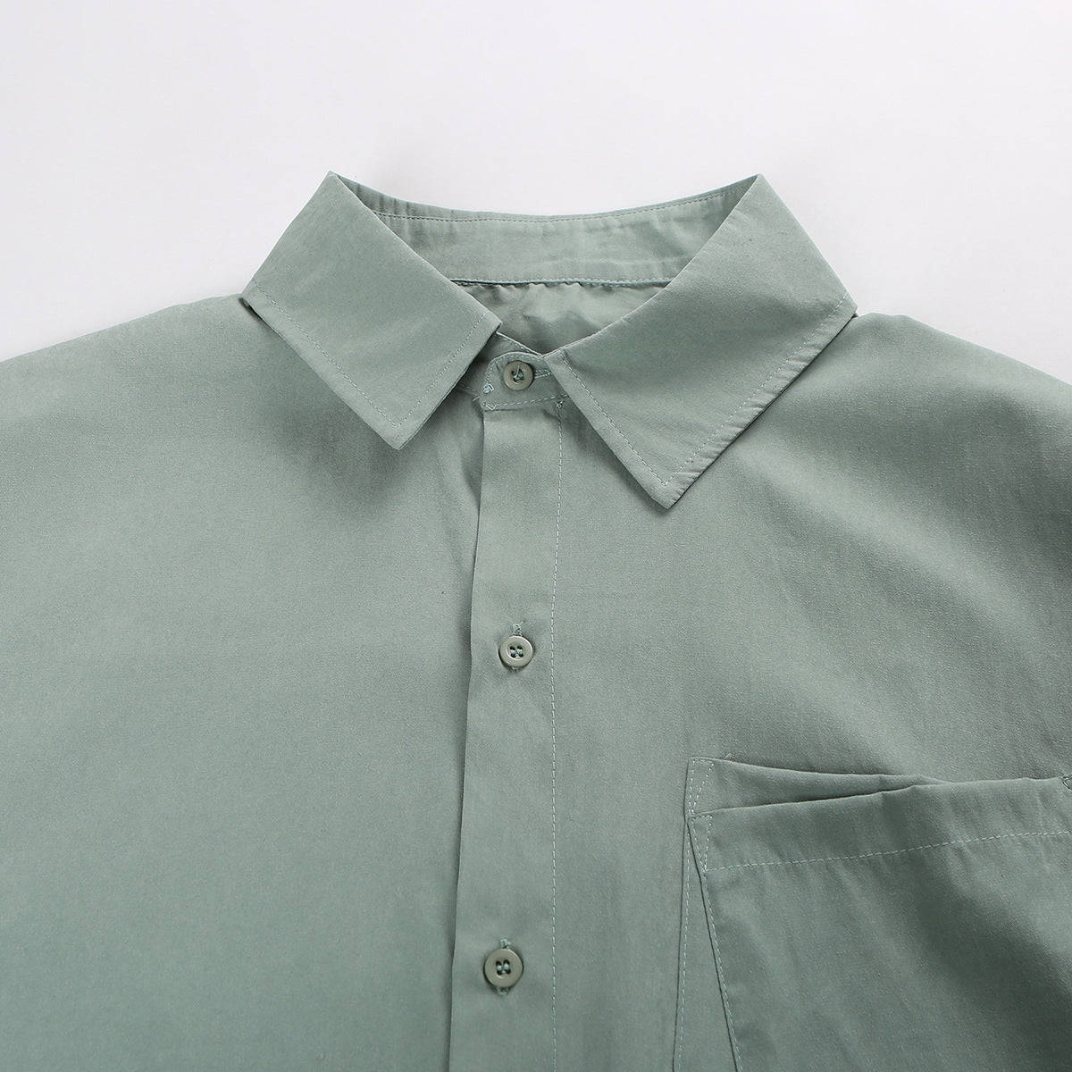 Close-up of the sage-green shirt's pointed collar, button placket, and chest pocket.