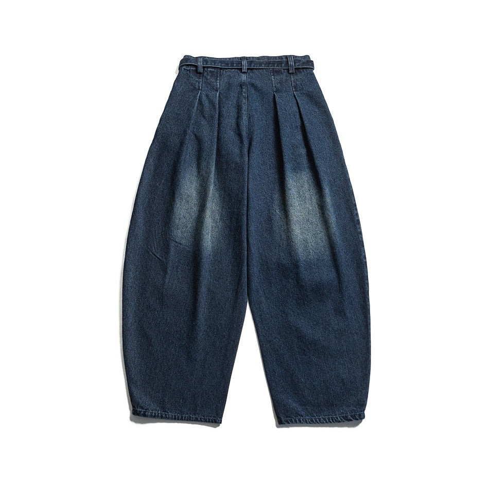 Back view of dark blue tapered trousers with a high waist, belt loops, and subtle faded patches.