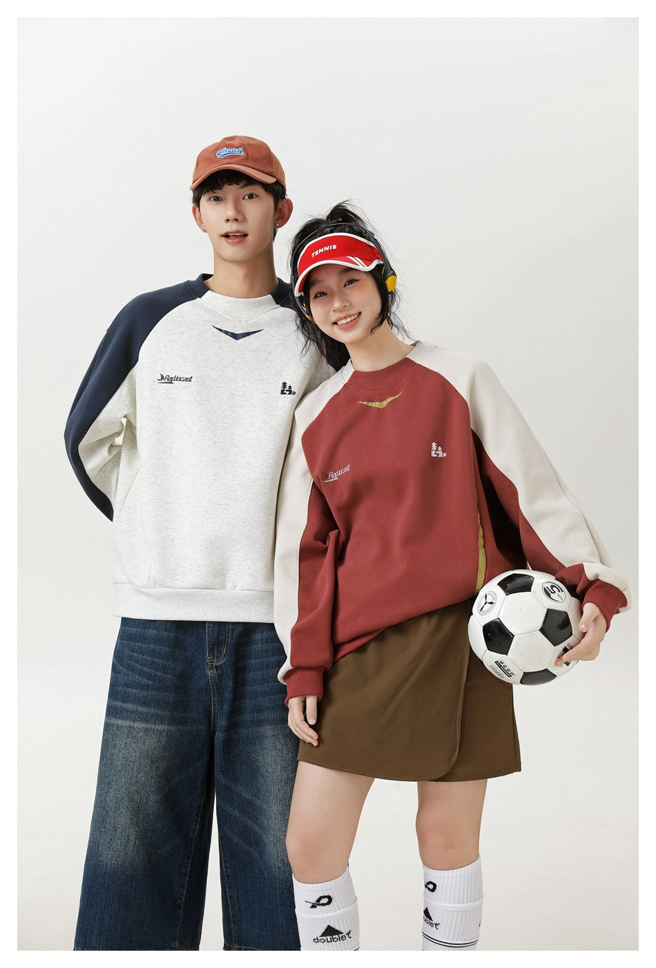 Two models wear color-block raglan sweatshirts: one cream and navy, the other rust and cream.