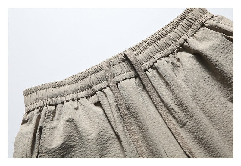 Close-up of taupe shorts showing the elastic waistband, drawstring and raised dotted texture.