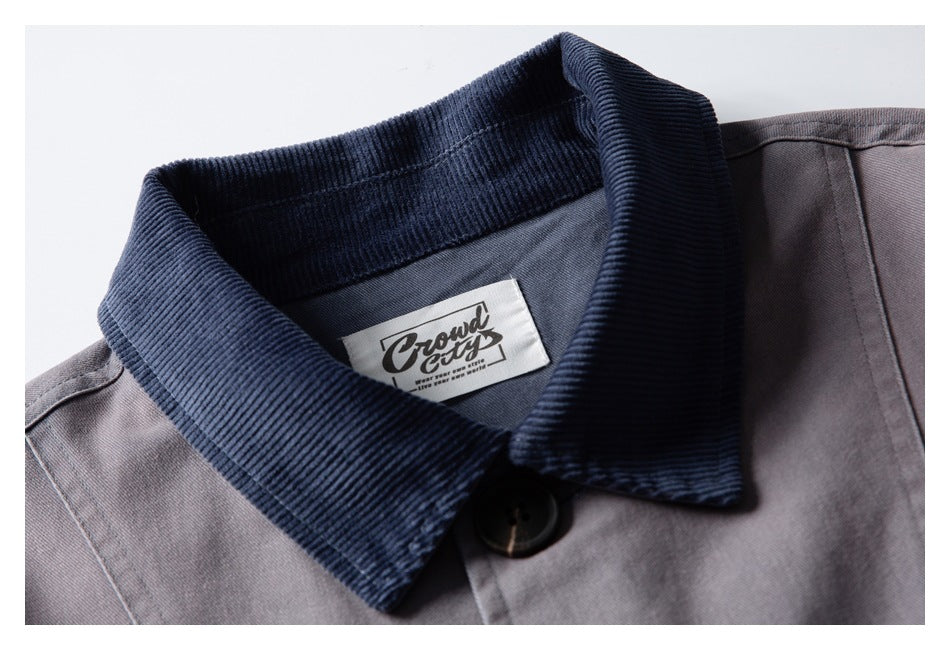 Close-up of a gray jacket with a dark navy corduroy collar, button, and sewn-in neck label.
