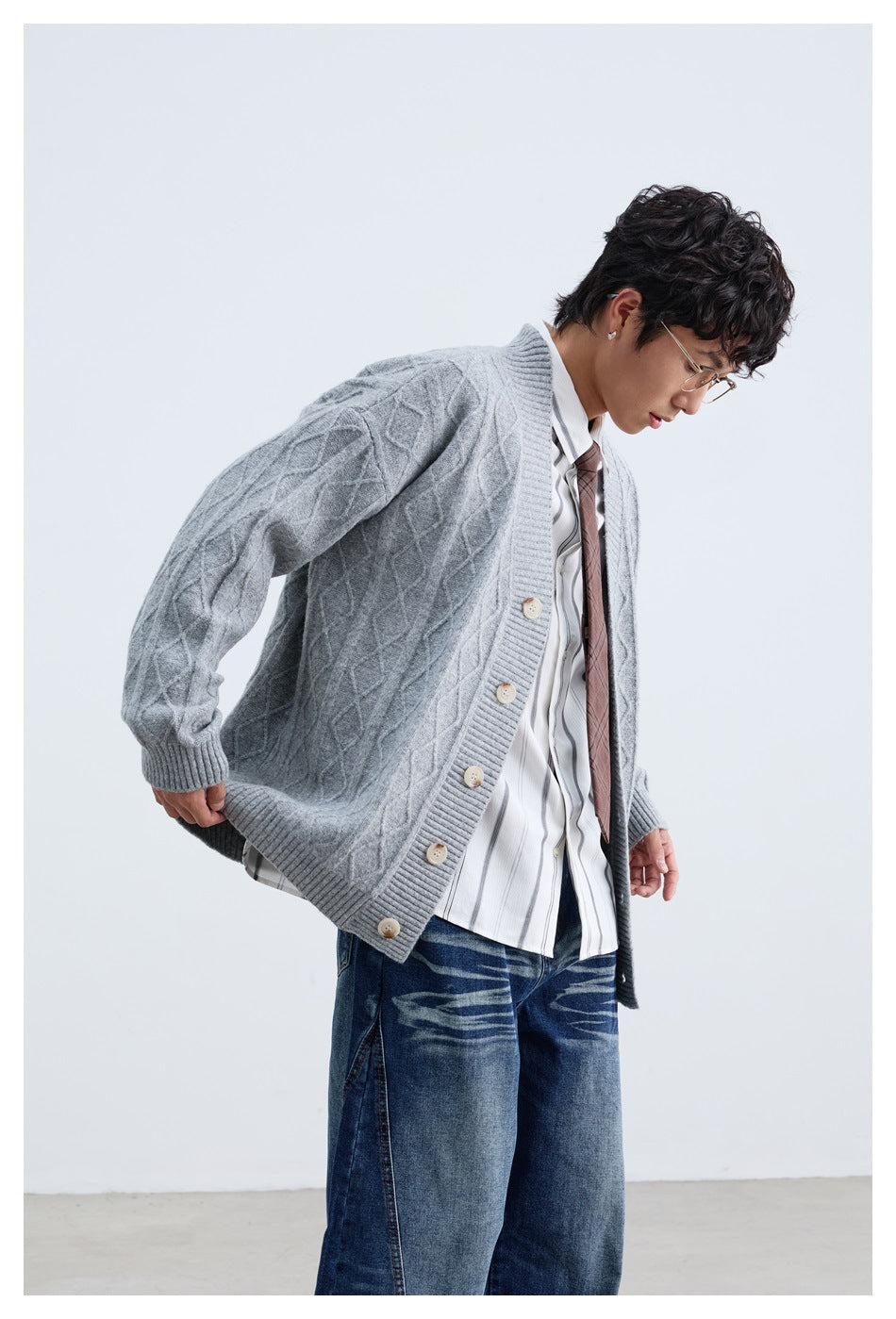 Model wearing a light gray cable-knit button-front cardigan over a striped shirt and tie.