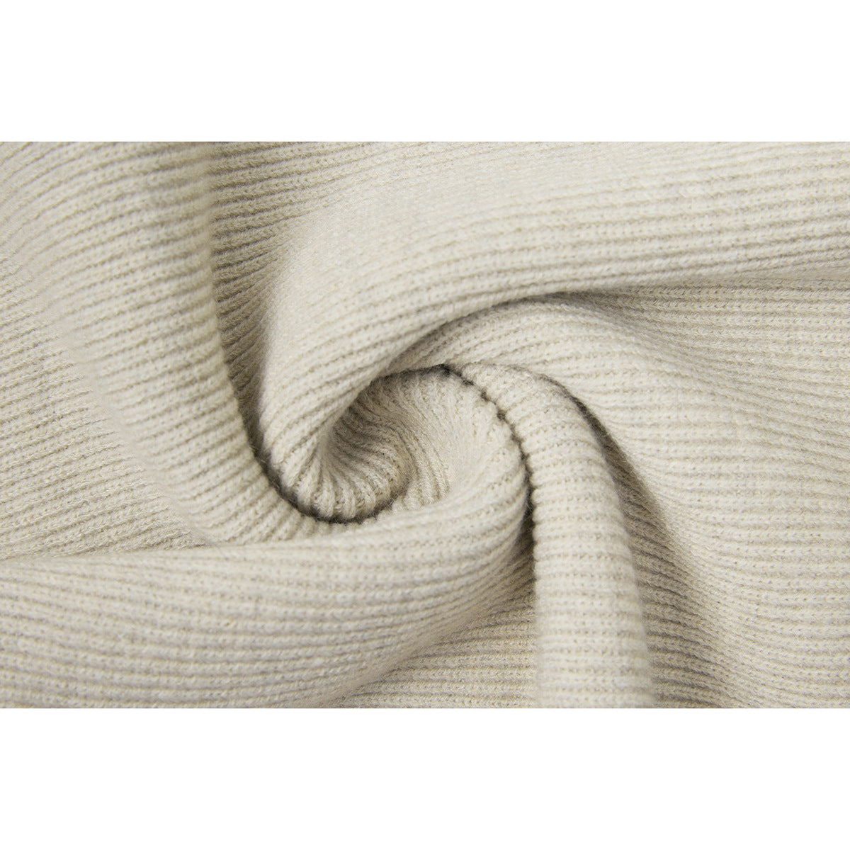 Close-up of cream-colored ribbed knit fabric folded to show its texture.