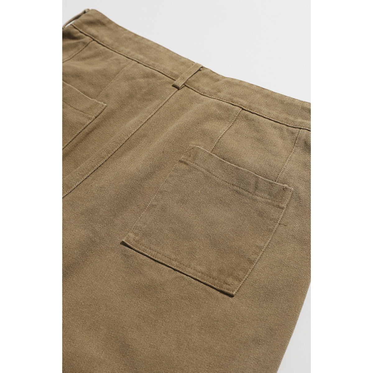Close-up of the back of tan shorts, showing the waistband and a large plain patch pocket.