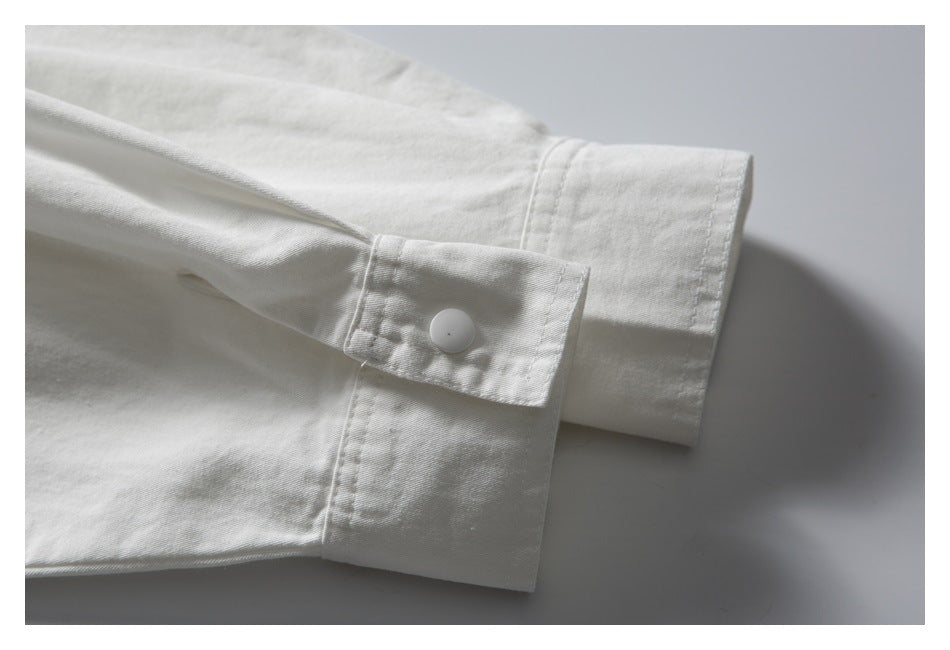 Close-up of a white sleeve cuff with a white button and visible stitching.