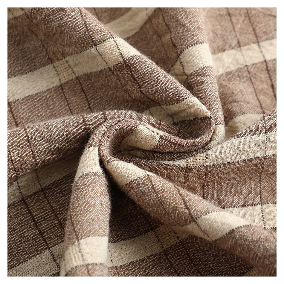 Close-up of brown and cream plaid fabric gathered to show its woven texture and pattern.