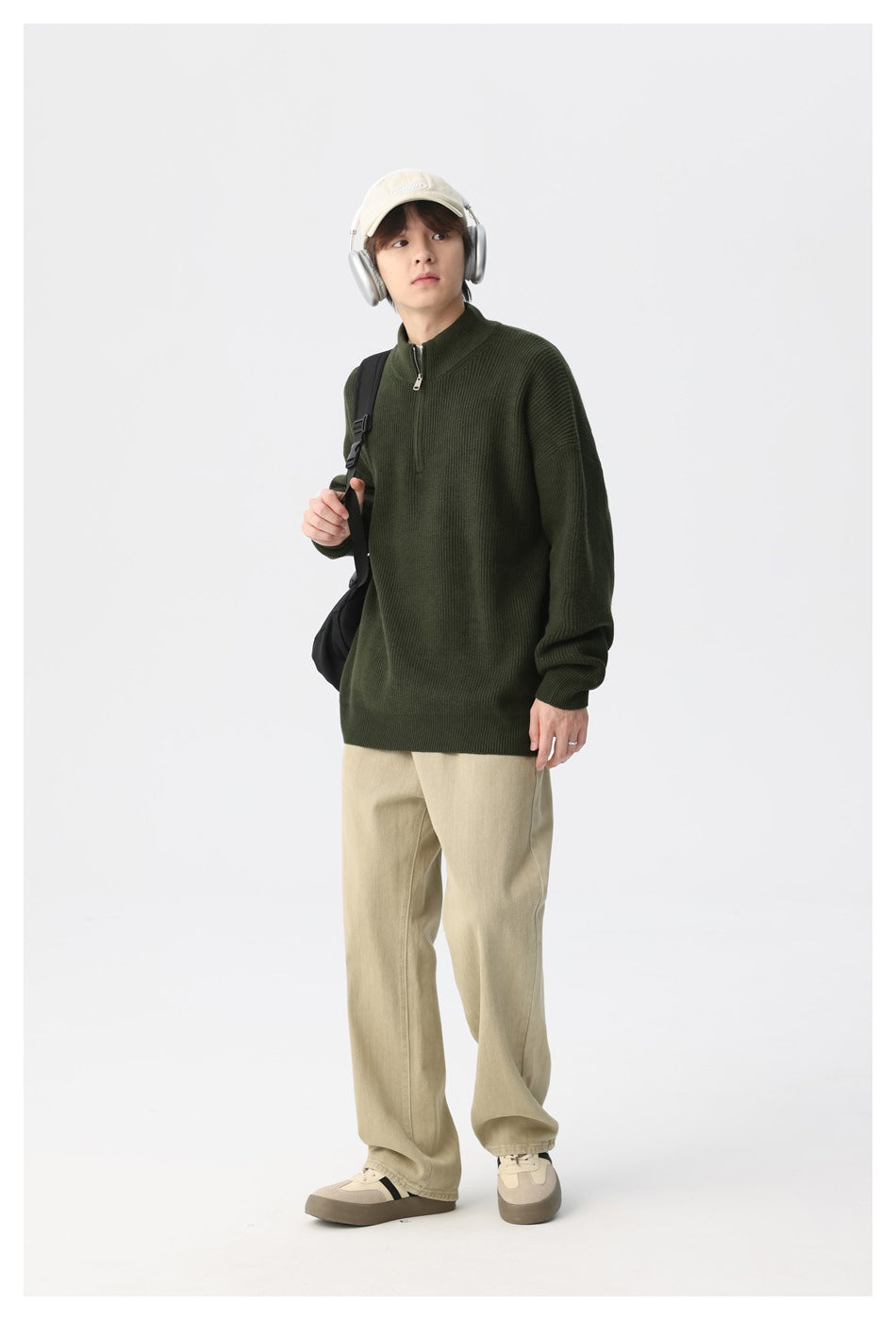 Model wearing a dark olive ribbed quarter-zip sweater and beige trousers, shown at a slight angle.