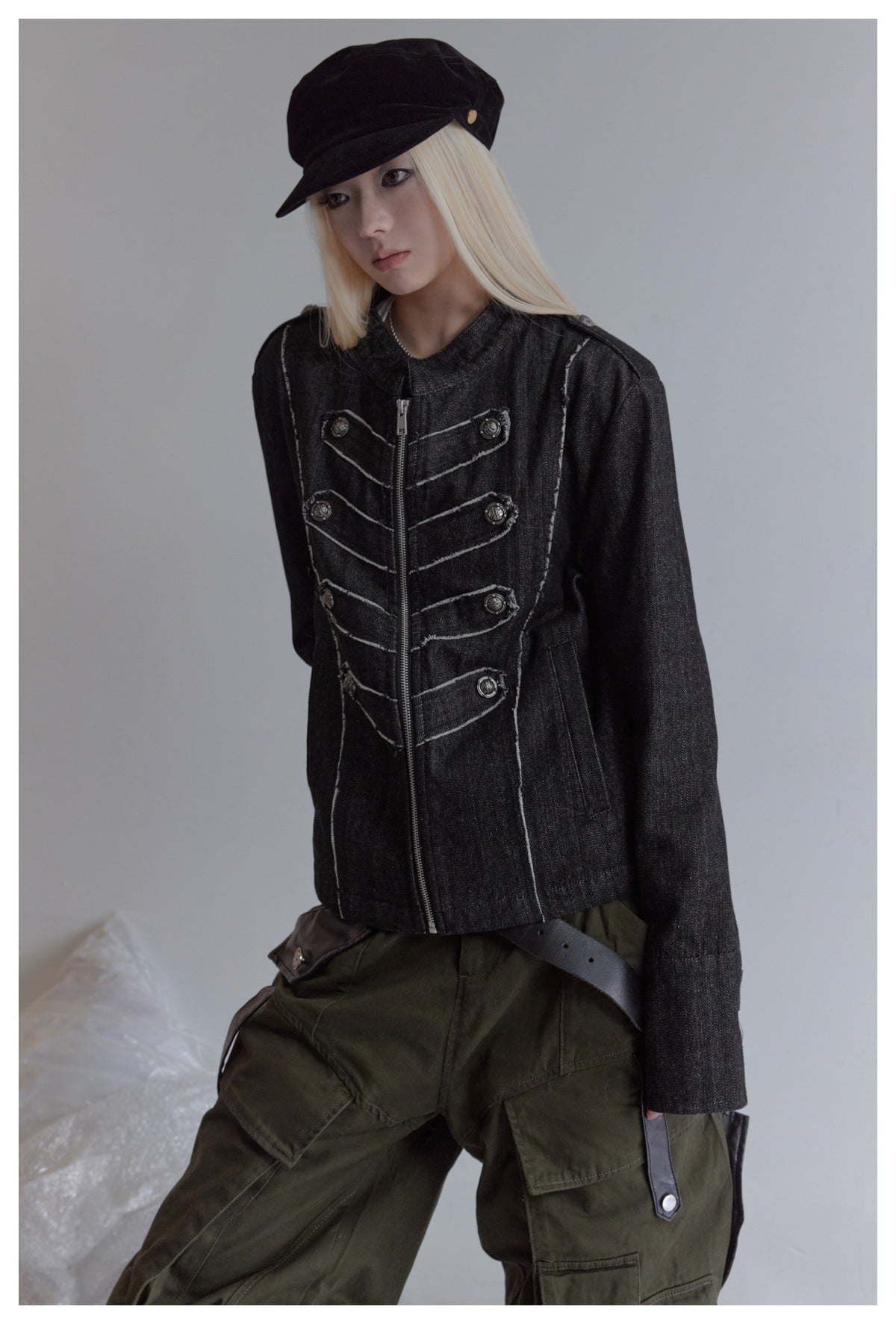 Model wearing a charcoal jacket with contrast seams, a front zipper and decorative buttons, paired with olive cargo pants.