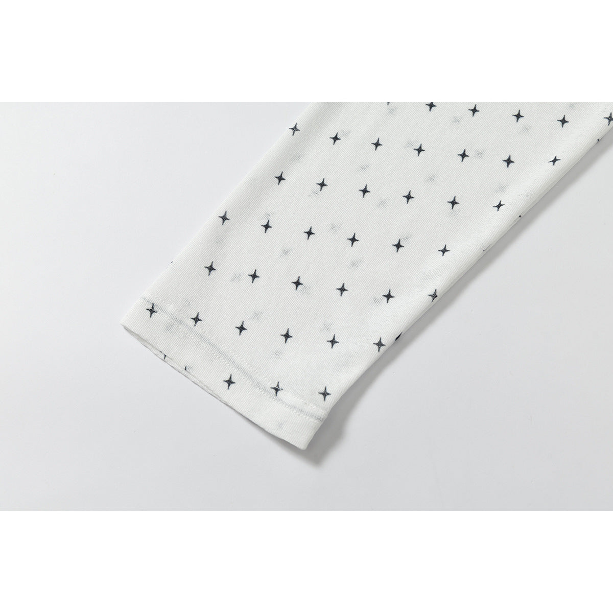 Close-up of a white sleeve with scattered black stars and a stitched cuff.