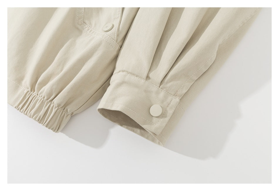 Close-up of the beige jacket's gathered hem and sleeve cuff with a snap button.