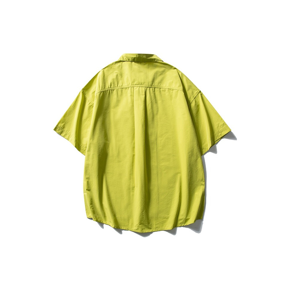 Back view of a bright yellow-green oversized short-sleeve button-up shirt with a center pleat.