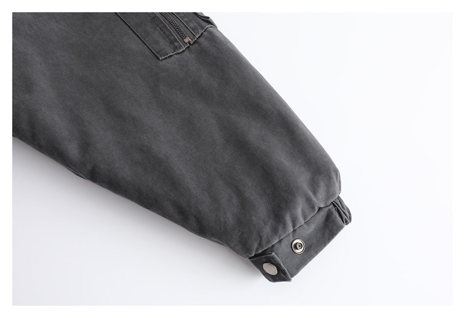 Close-up of a charcoal garment sleeve with a snap-fastened cuff and a zippered pocket.