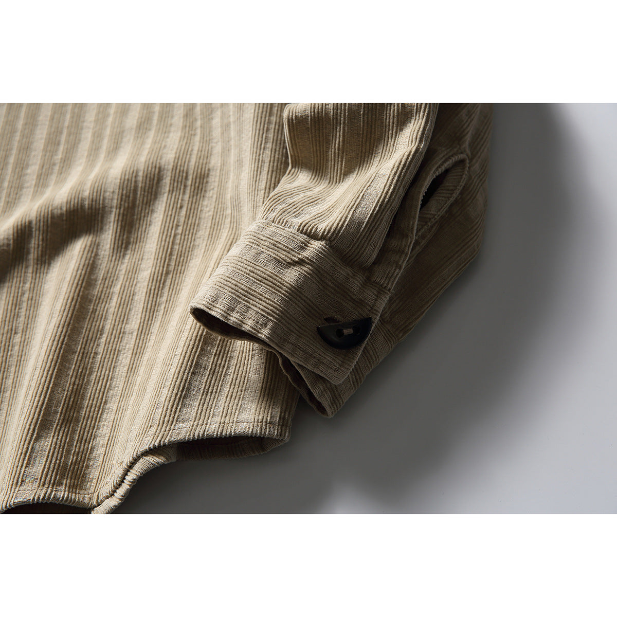Close-up of the beige striped shirt’s long sleeve, buttoned cuff, and hem.