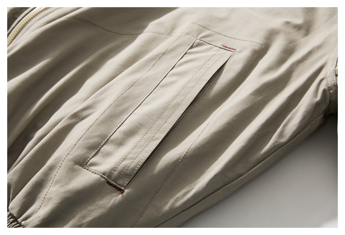 Close-up of a long welt pocket with red bar tacks on a beige jacket.