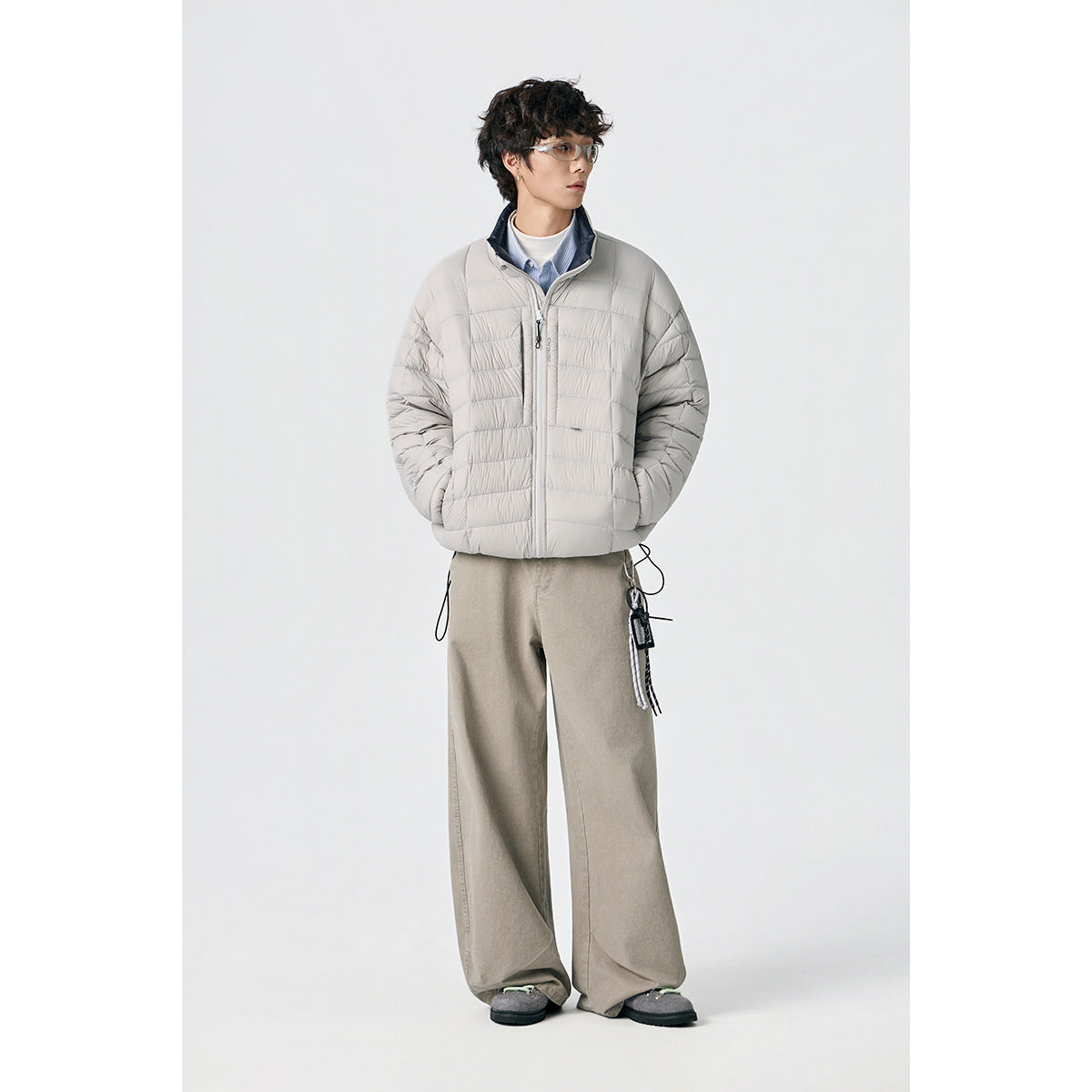 Model wearing a light gray quilted zip-up jacket with a stand collar and horizontal baffles.