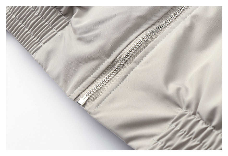 Close-up of a light gray jacket zipper and gathered elastic hem.