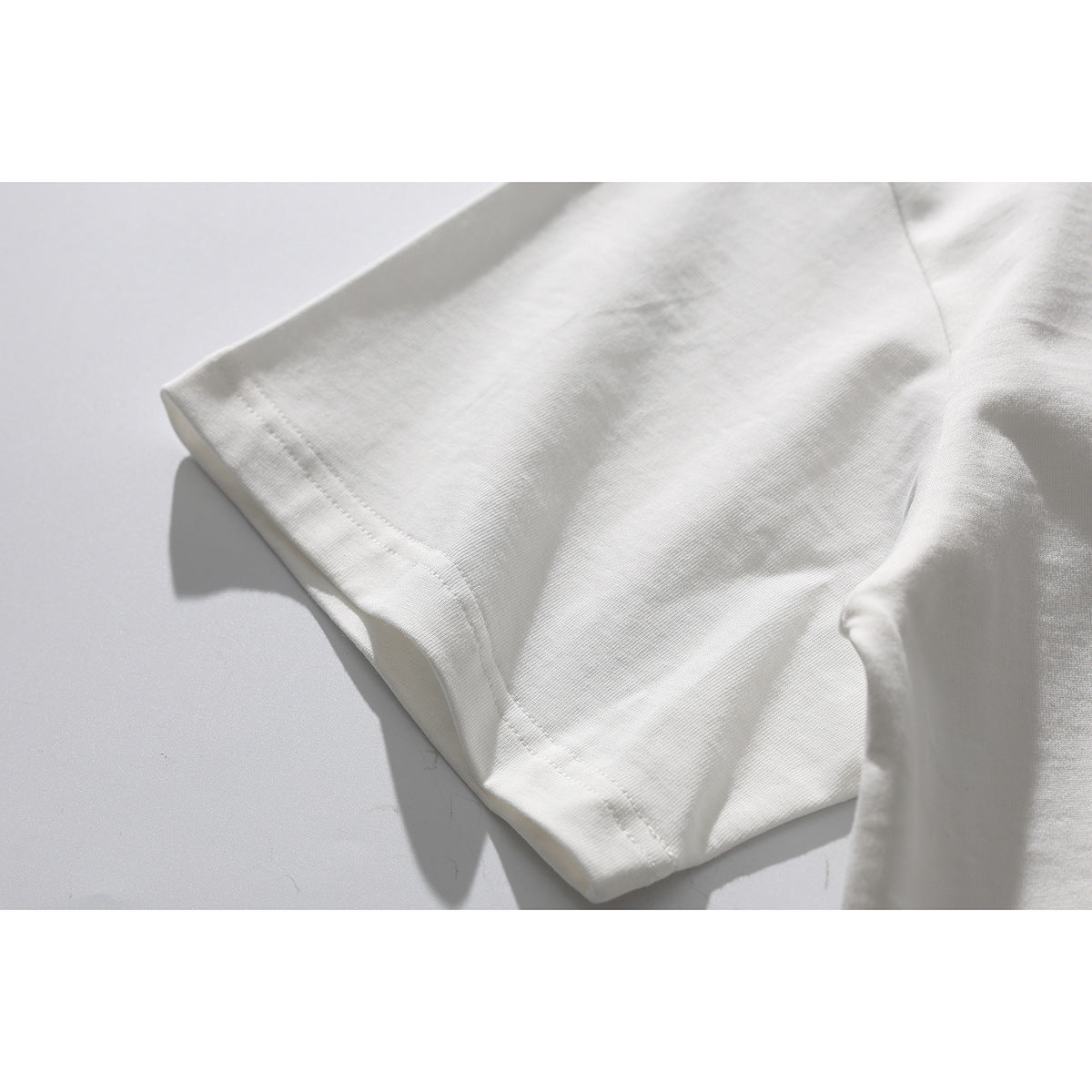 Close-up of a white T-shirt sleeve and double-stitched hem.