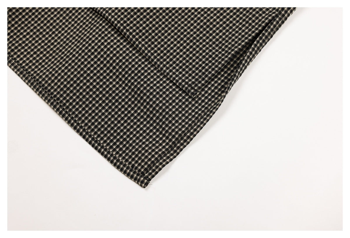 Close-up of a pointed edge and stitched seam on black and beige small-check garment fabric.