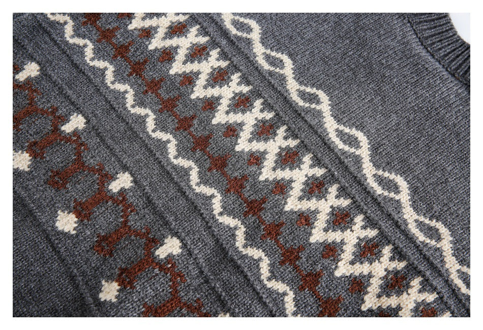 Close-up of a charcoal gray knit garment with cream and rust geometric patterns and a ribbed edge.
