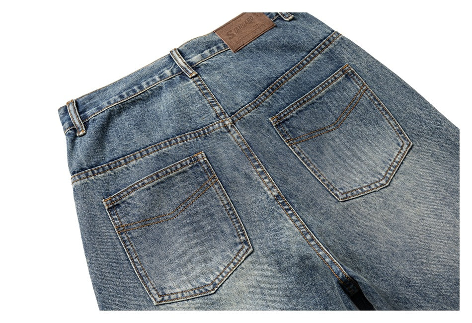 Close-up rear view of faded blue jeans, showing two back pockets, waistband, and a brown patch.