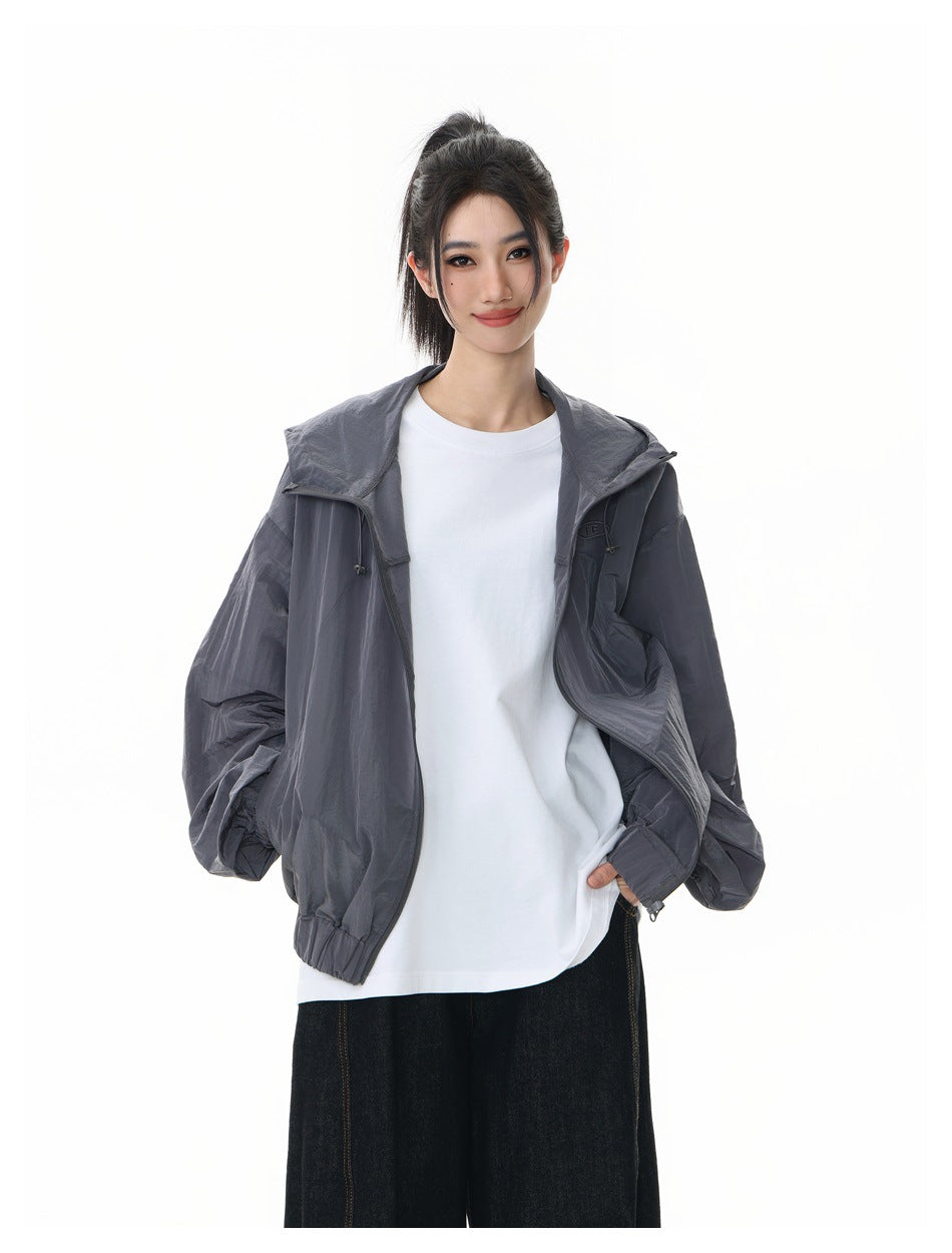 Model in open gray hooded jacket over white t-shirt, close-up with hand in pocket