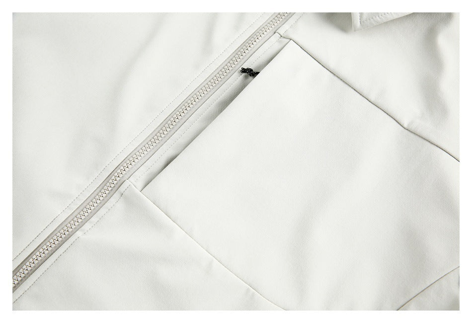 Close-up of an ivory garment with a diagonal front zipper and a large stitched panel.