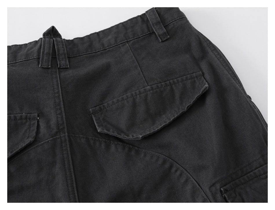 Close-up of the back waistband of black cargo pants, with a drawstring, belt loops, and flap pockets.
