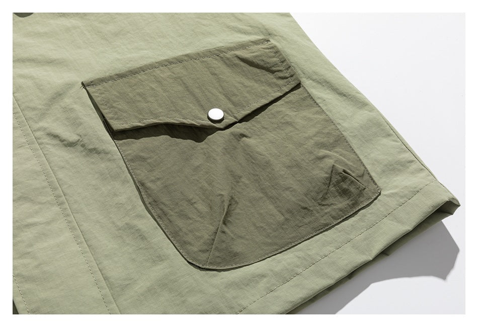 Close-up of a large darker olive flap pocket with a snap on an olive-green jacket.