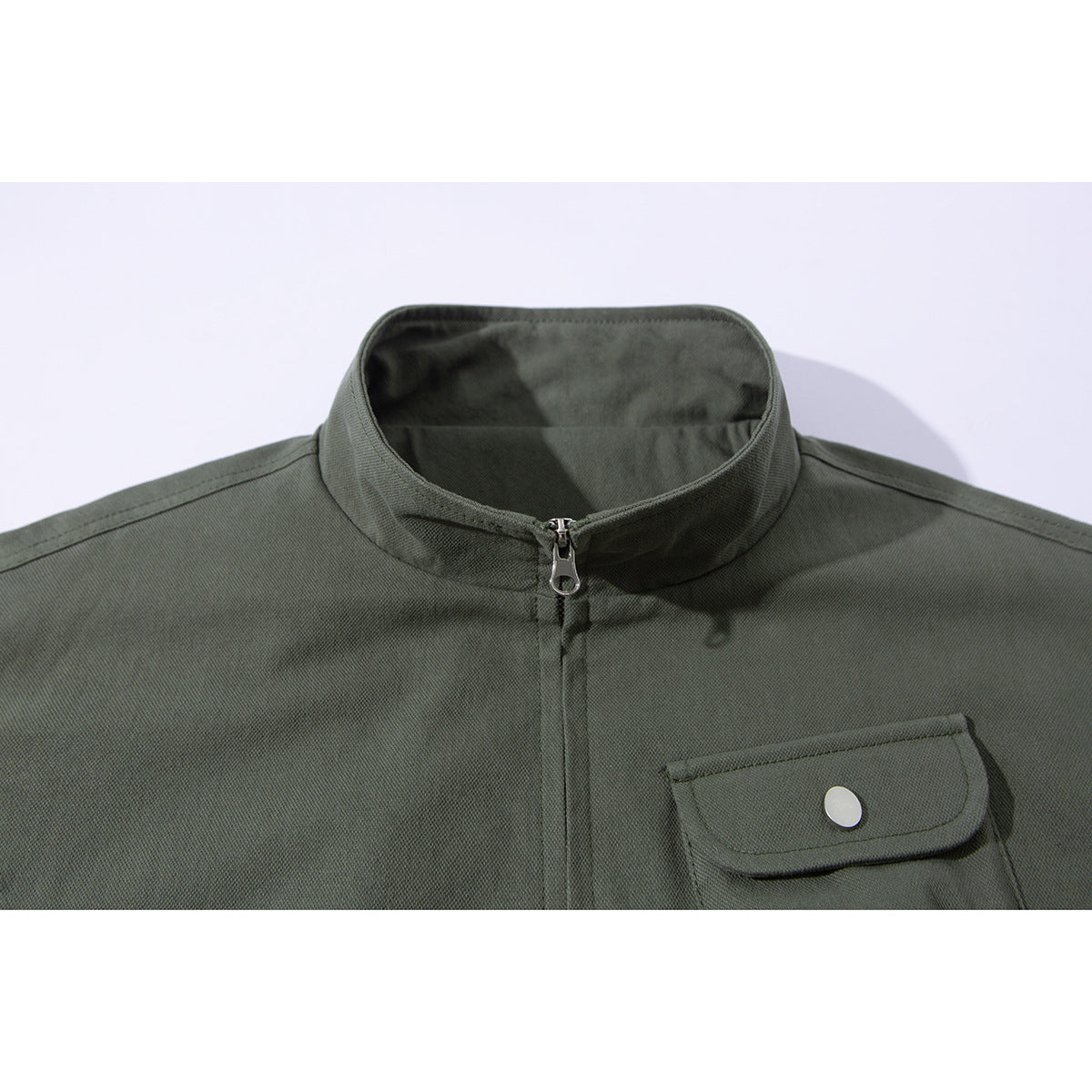 Close-up of an olive jacket's stand collar, front zipper, and flap chest pocket with a snap button.