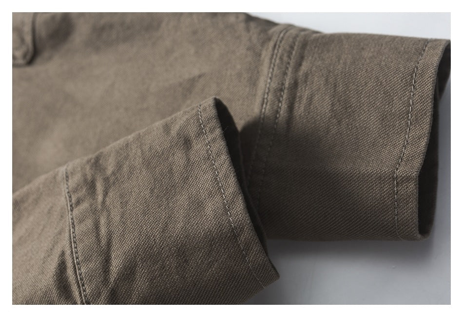 Close-up of the olive-brown shirt sleeve cuff, showing its button and stitched seams.