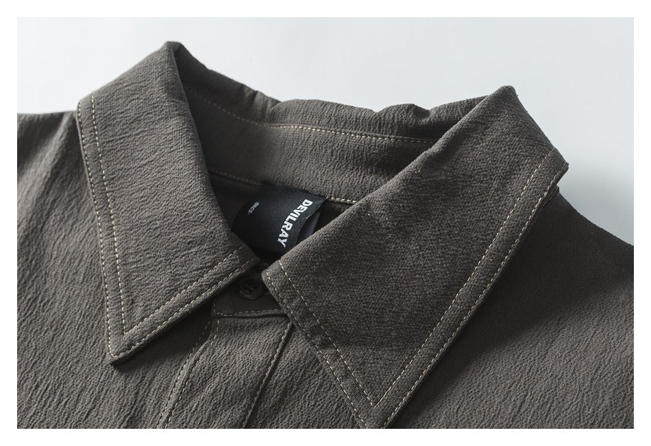 Close-up of the shirt's pointed collar, contrast topstitching, and black neck label with white lettering.