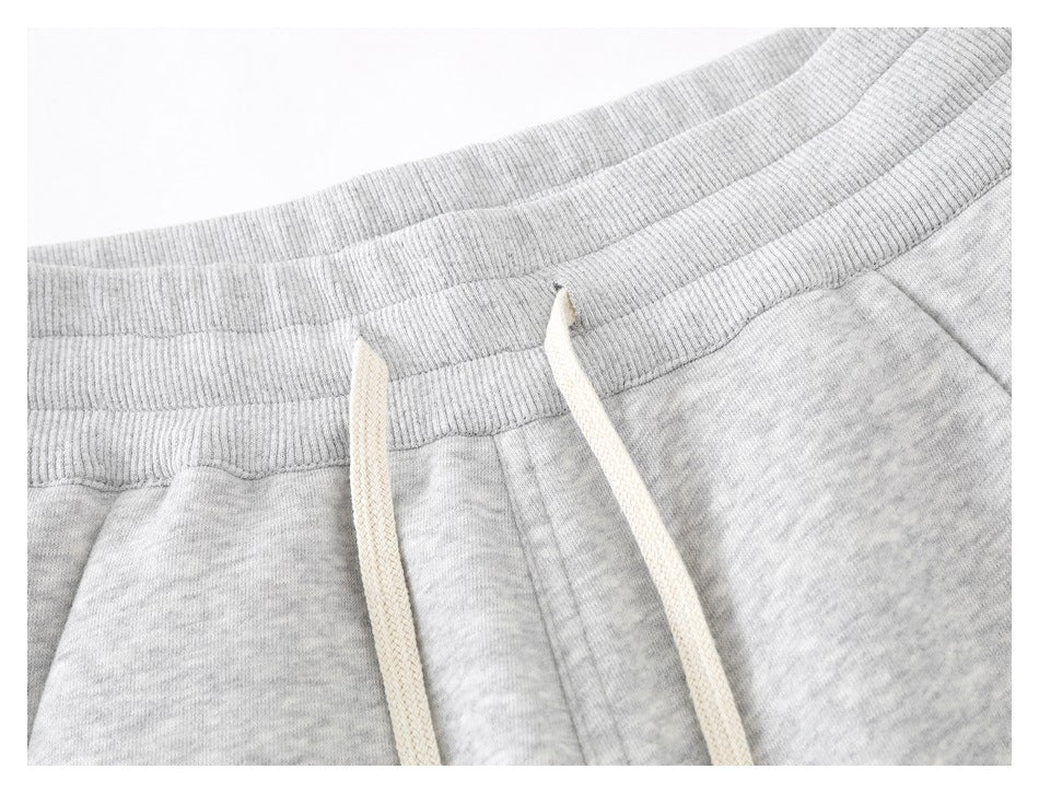 Close-up of the ribbed waistband and cream drawstrings on light gray melange pants.