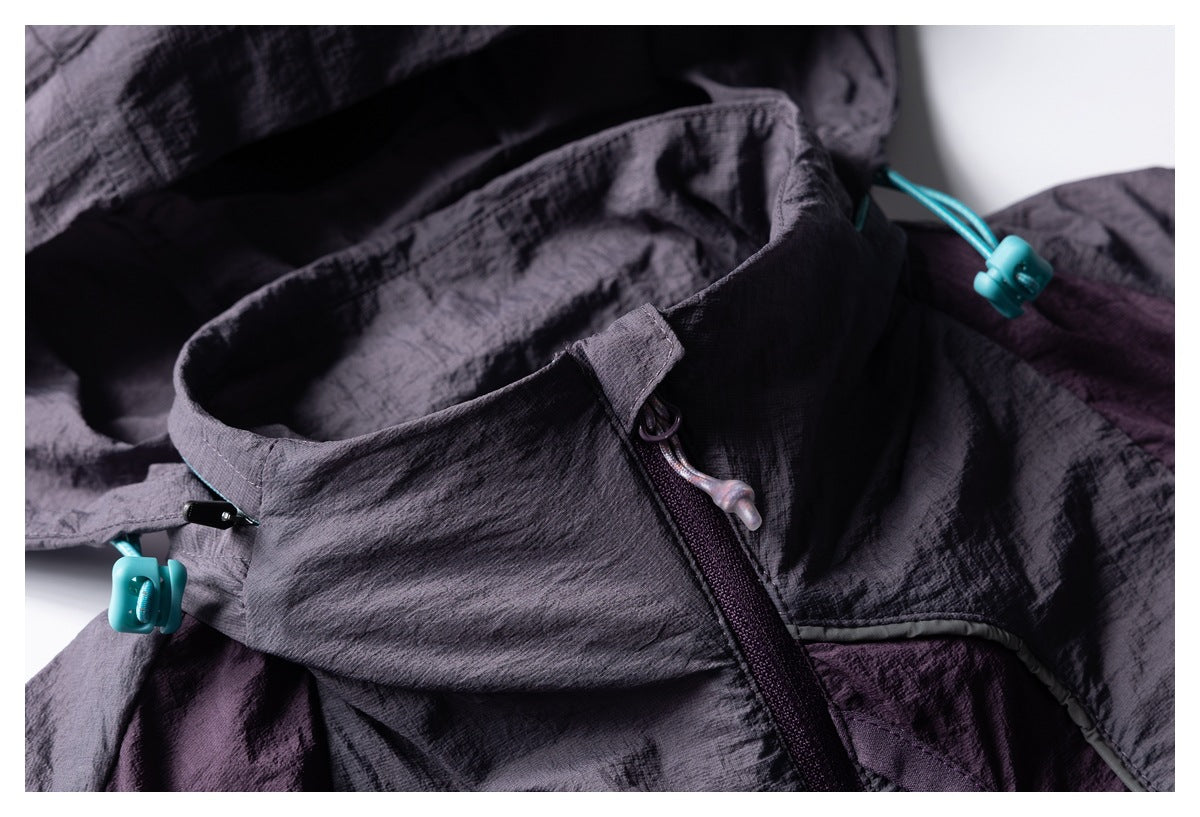 Close-up of a dark gray-purple jacket collar, zipper, and bright turquoise drawcord toggles.