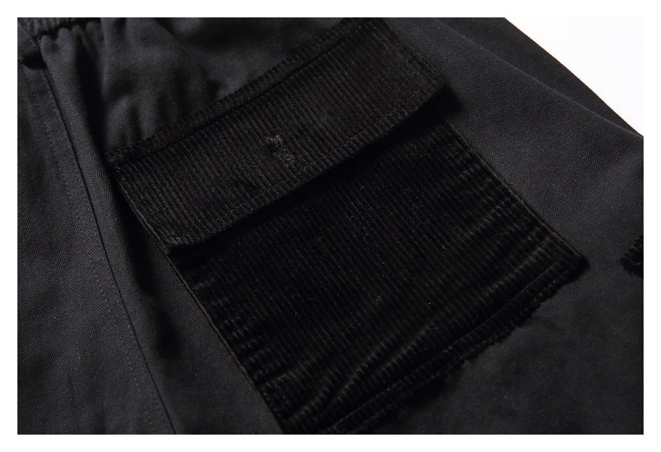 Close-up of a black shorts pocket with a wide ribbed black panel and matching stitching.