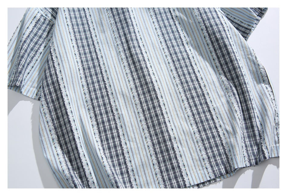 Cropped flat view of a shirt back and sleeve in light blue fabric with alternating plaid and striped bands.
