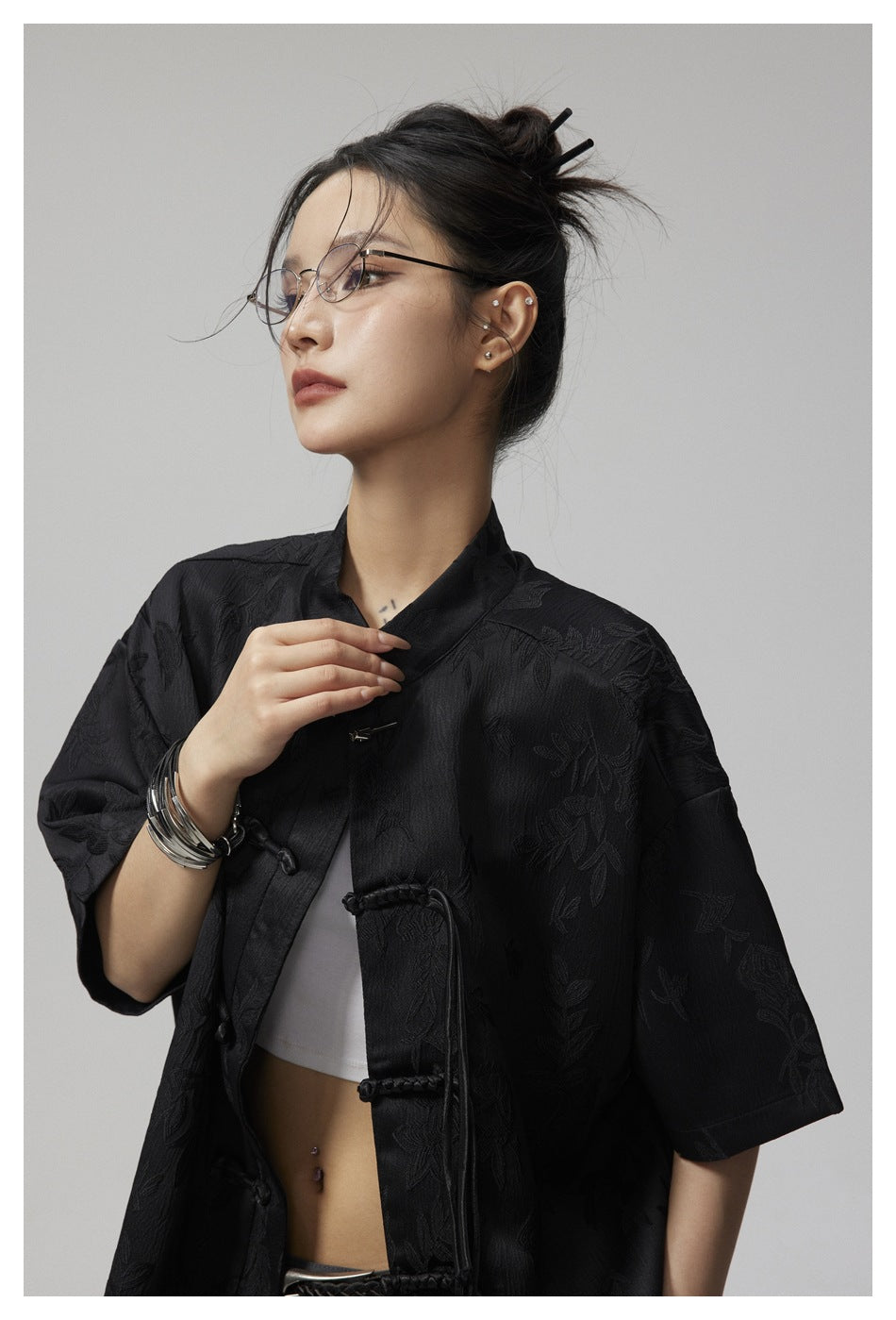 Close-up of a model wearing a black floral jacquard shirt with a stand collar and frog closures.