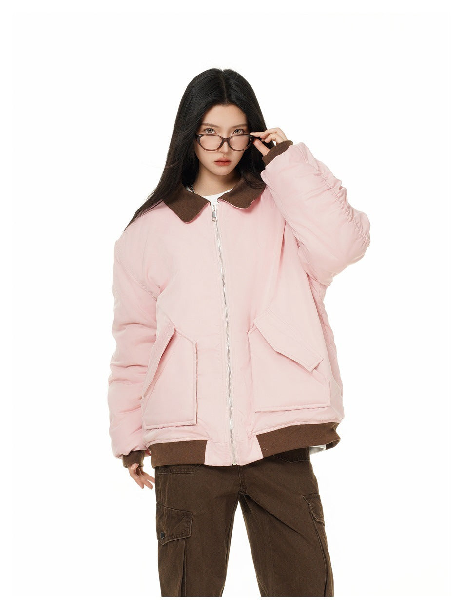 Model in a pink zip jacket with brown collar and flap pockets, touching her glasses, with brown cargo pants