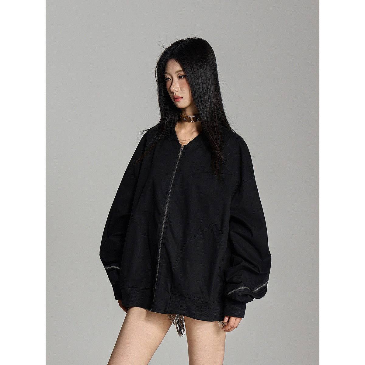Model wearing an oversized black zip-front jacket with voluminous sleeves and zip details near the cuffs.