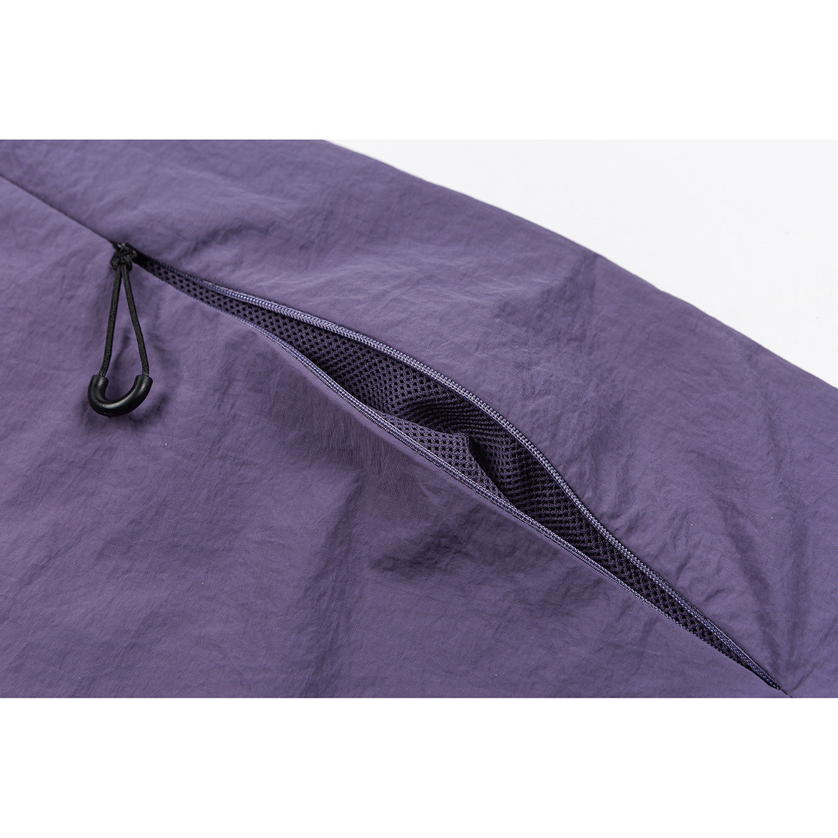 Close-up of purple pants showing a diagonal mesh-lined zip pocket with a black pull.