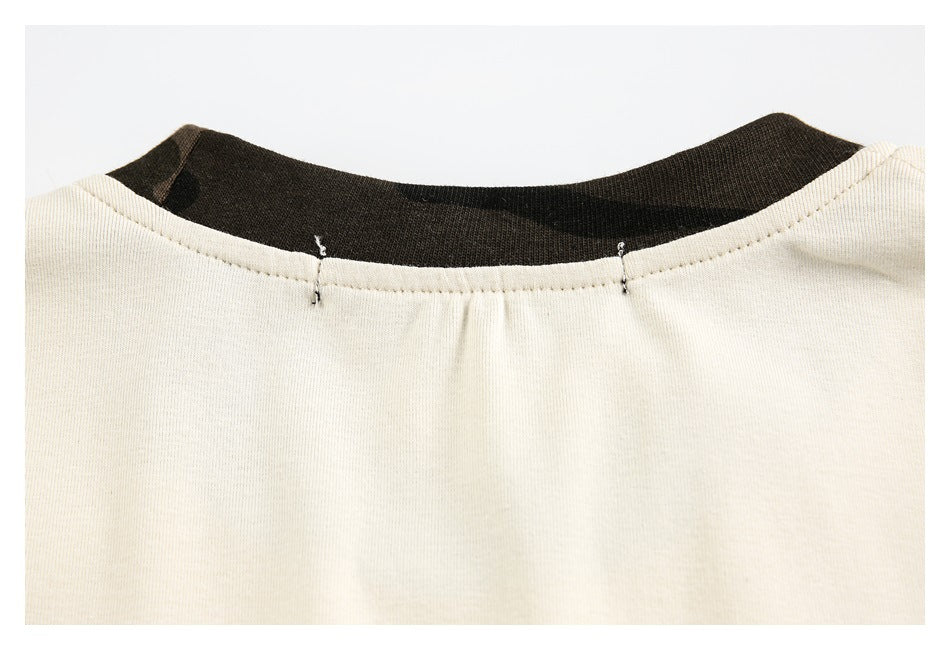 Close-up of a cream garment neckline with a dark inner facing and small tack stitches.