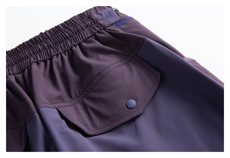 Close-up of a flap pocket and stitched panels on the purple shorts.