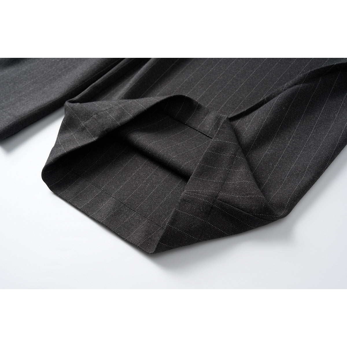 Close-up of a trouser leg hem folded back to show the charcoal pinstripe fabric and stitching.