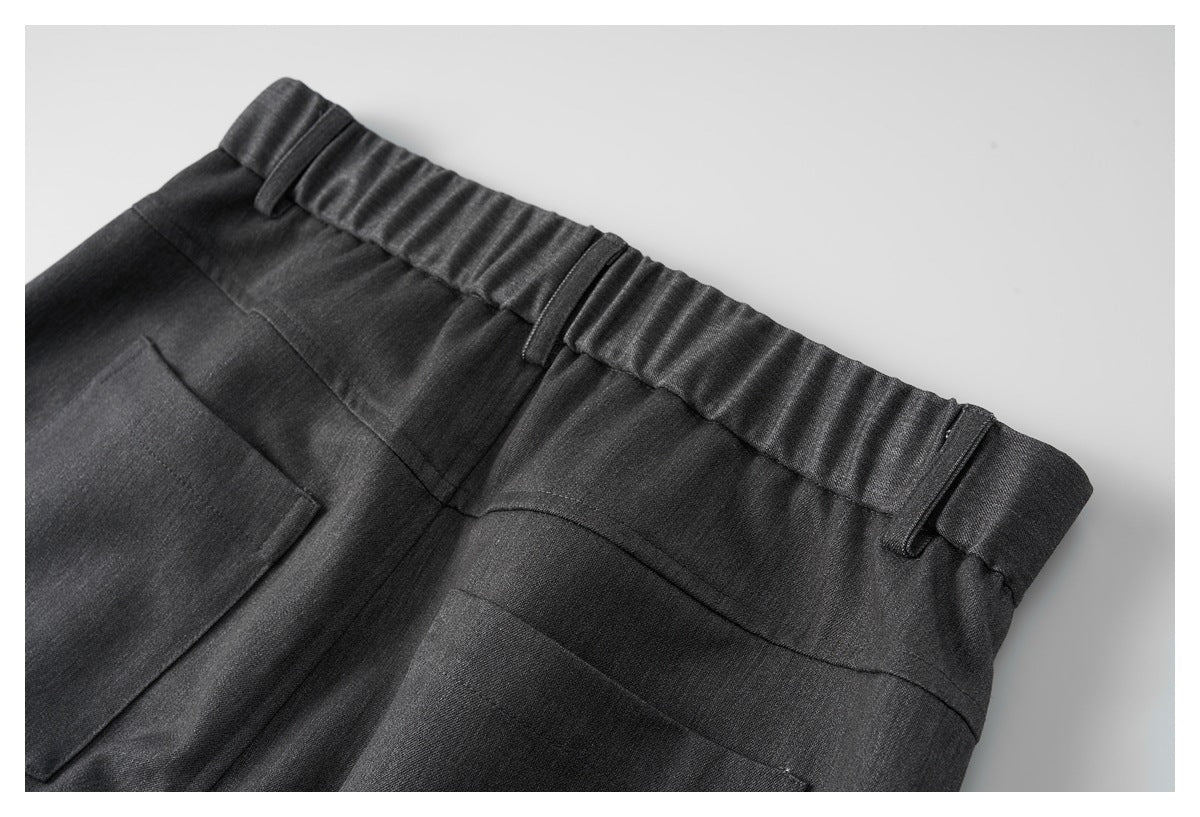 Close-up of the back waistband of charcoal trousers with belt loops and rear pockets.
