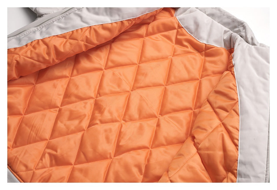 Close-up of a light gray jacket opened to show its bright orange diamond-quilted lining and zipper edge.