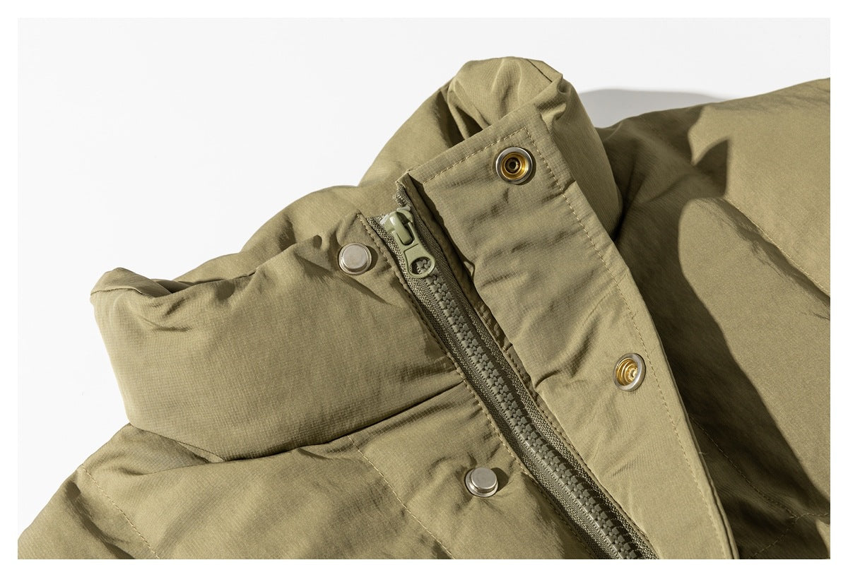 Close-up of an olive-tan padded jacket zipper and snap-button storm flap.