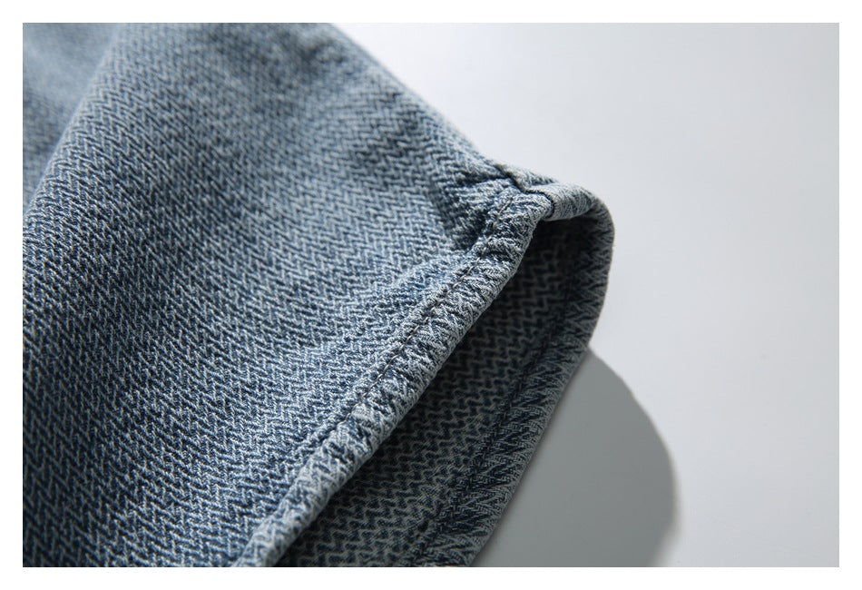 Close-up of the dark patterned denim panel and its folded, stitched edge.