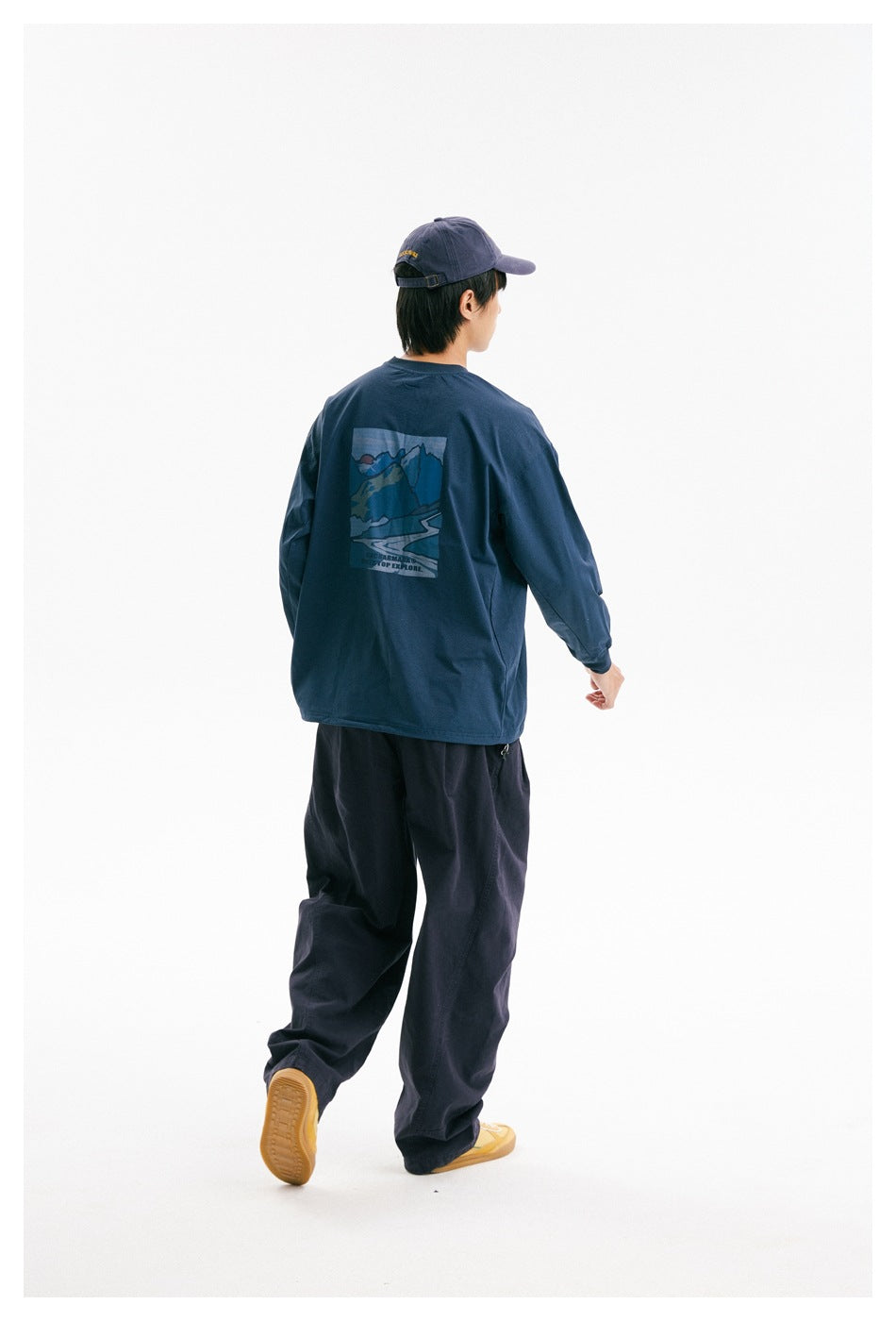 Rear view of a model wearing a navy long-sleeve shirt with a large blue mountain graphic on the back.
