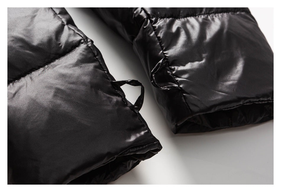 Close-up of the lower edge and cuff area of a glossy black padded jacket.